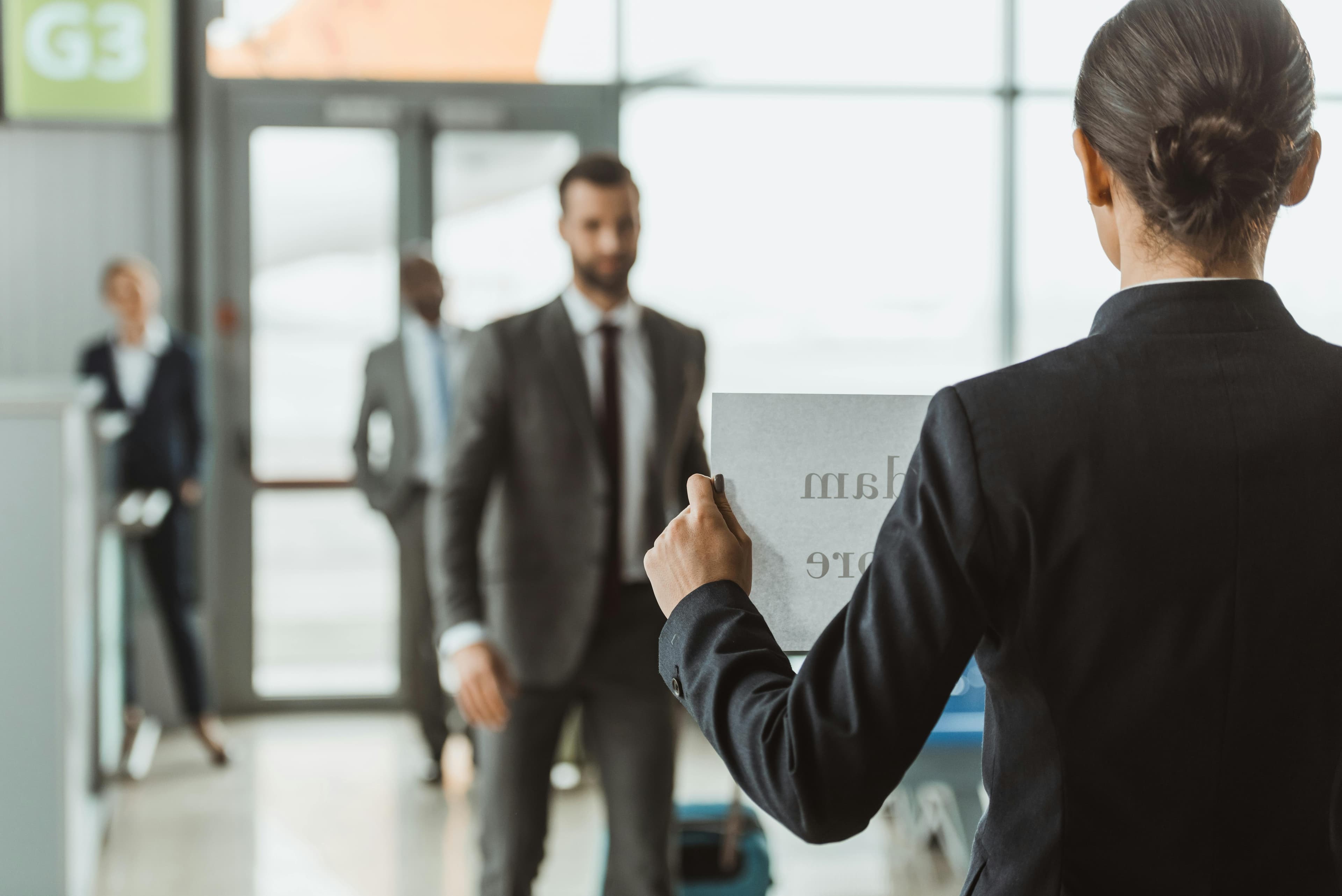 Female chauffeur holding a name board in the arrivals hall at an Airport